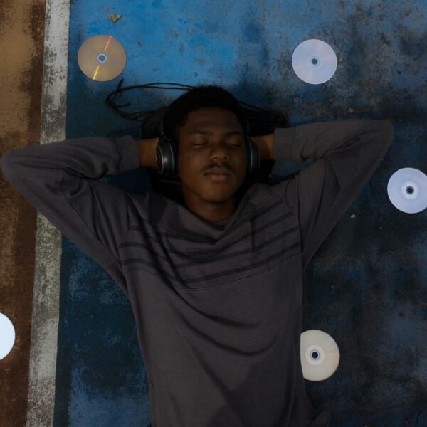 Man in headphones relaxing with CDs around on a sports court.